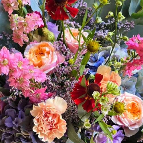 Farbenreiches Blumengesteck mit Rosen, Hortensien und Nelken