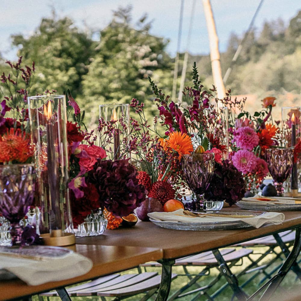 Herbstliche Tischdekoration mit Blumen, Feigen und Stabkerzen im Windlichtglas
