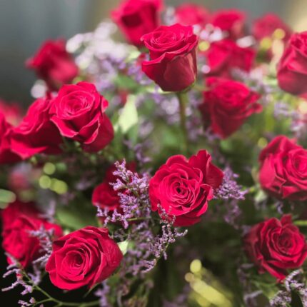 Großer Blumenstrauß aus roten Rosen mit violettem Strandflieder