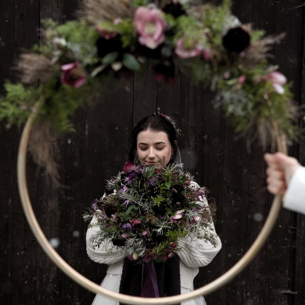 nga mit winterlichem Brautstrauß in einem teilweise bewickelten Blumenkranz