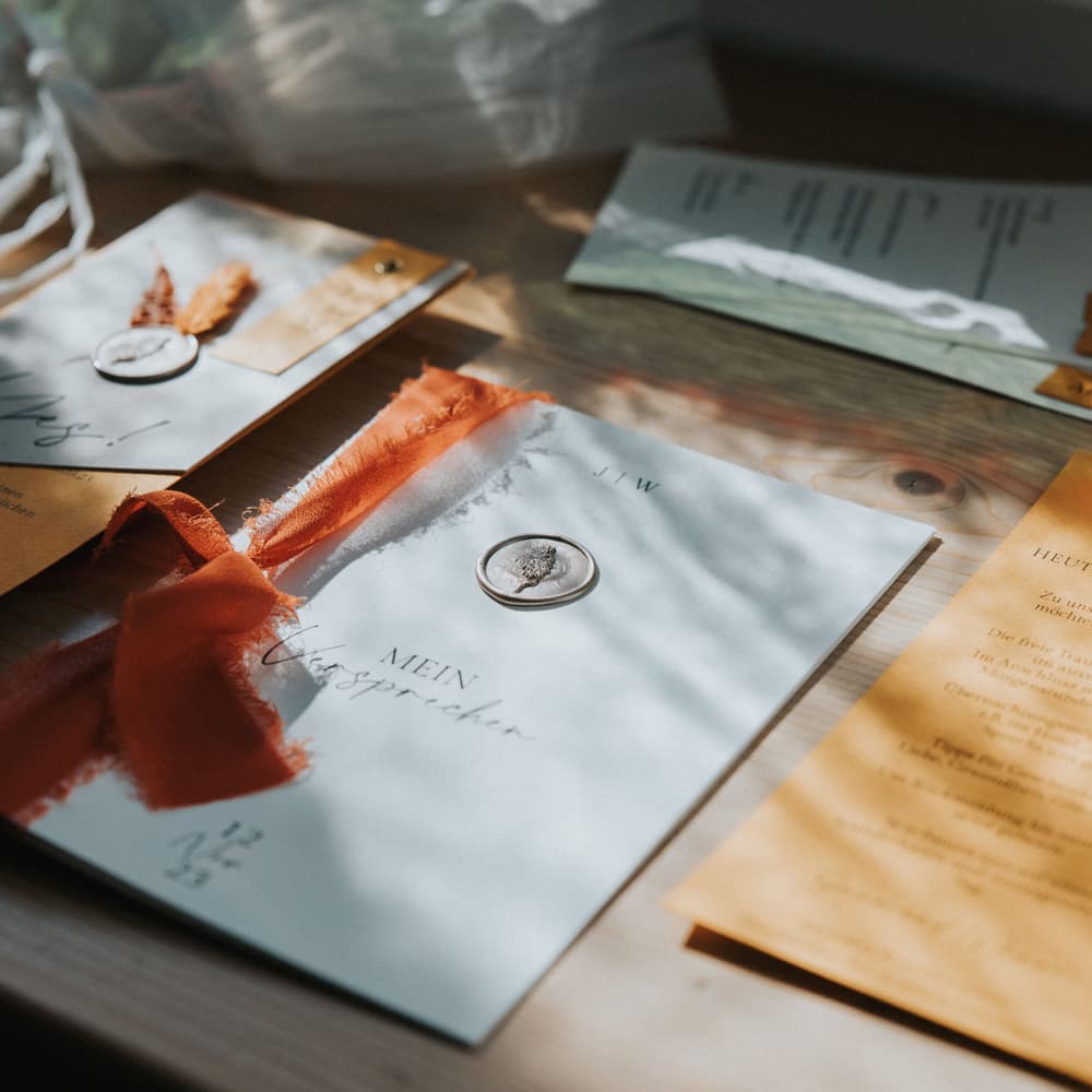 Hochzeitspapeterie mit orangefarbenen Seidenbändern und Wachssiegeln
