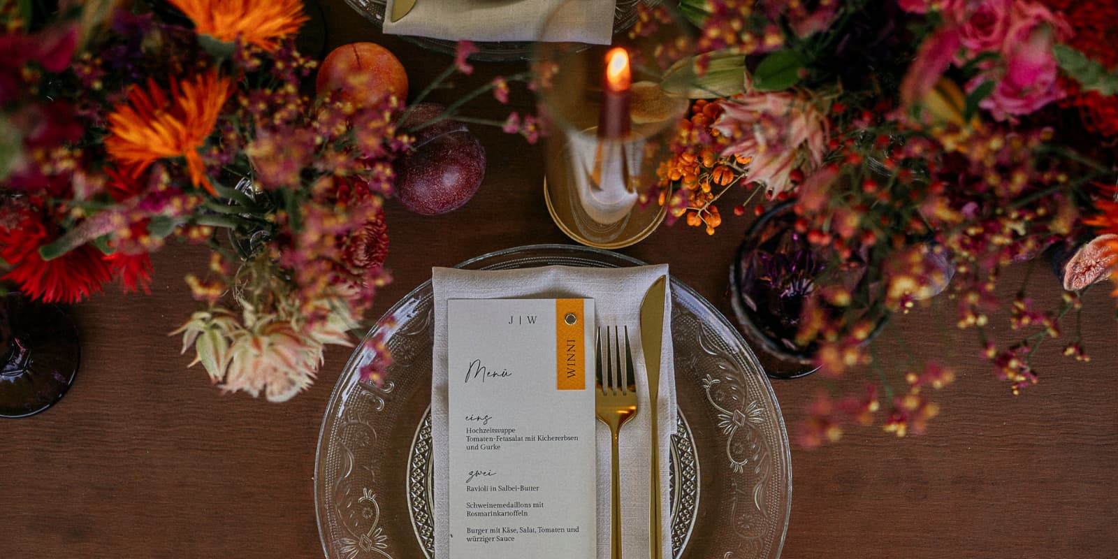 Herbstliche Hochzeitstafel mit Blumen, Feigen, Glassteckern und Kerzen