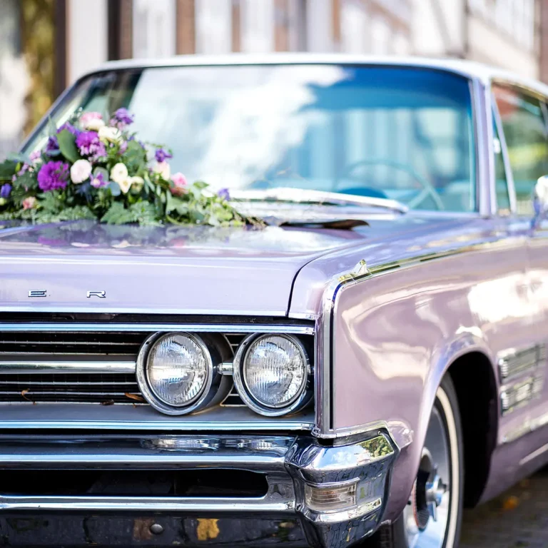 Violetter Oldtimer mit pastellfarbenem Blumenschmuck. Hochzeitsfloristik von paeonia.